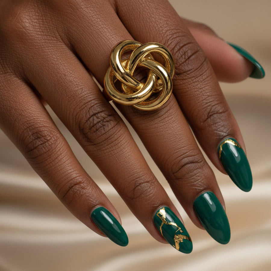 Close-up of a hand with green nails wearing the gold Harmony interlocking ring.