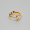 A gold-colored adjustable ring with a teardrop-shaped clear stone set on top.