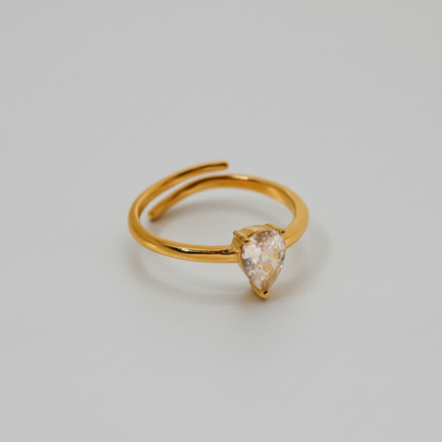 A gold-colored adjustable ring with a teardrop-shaped clear stone set on top.